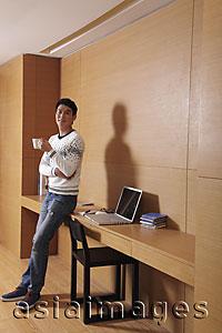 Asia Images Group - Young man leaning on his desk drinking coffee