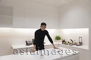 Asia Images Group - Young man dressed in black standing in modern office