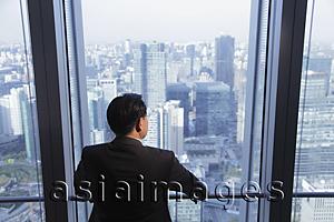 Asia Images Group - Rear view of man looking out the window at a city view, Beijing, China