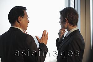 Asia Images Group - Two men talking in front of window