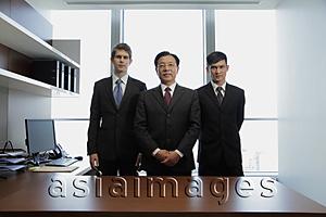 Asia Images Group - Three business men standing behind a desk