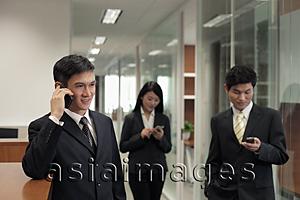 Asia Images Group - Three businesspeople using their phones in the office