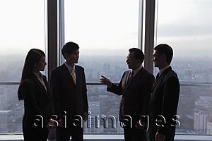 Asia Images Group - Four businesspeople talking in front of a window