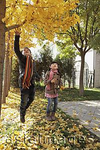 Asia Images Group - Young boy and girl playing in the Autumn leaves outdoors