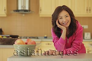 Asia Images Group - Young woman wearing pink smiling in her kitchen