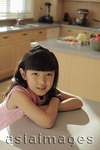 Asia Images Group - Young girl sitting at the kitchen counter