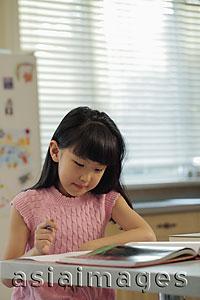 Asia Images Group - Young girl studying in the kitchen