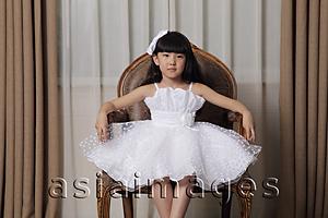 Asia Images Group - Young girl dressed up in white dress and sitting on nice chair