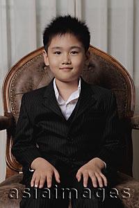 Asia Images Group - Young boy wearing a suit sitting on a chair