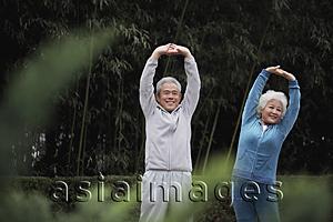 Asia Images Group - Senior man and woman stretching together outdoors