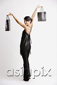 AsiaPix - Young woman carrying shopping bags, looking over shoulder