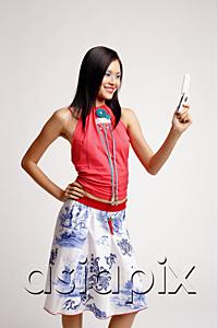 AsiaPix - Young woman looking at mobile phone, hand on hip
