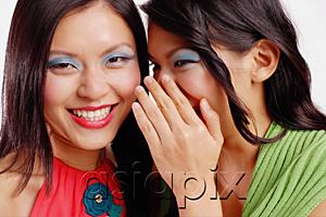 AsiaPix - Two women, one smiling at camera, the other whispering to her