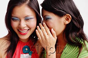 AsiaPix - Two women, one looking downwards, the other whispering in her ear