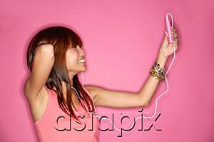 AsiaPix - Young woman holding mp3 player, looking up, hand behind head