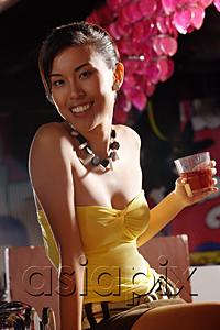 AsiaPix - Young woman holding drink, looking at camera