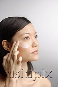 AsiaPix - Woman applying moisturizer, side view