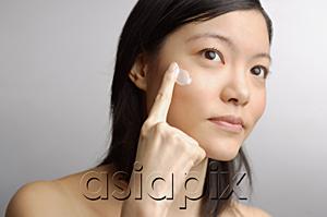AsiaPix - Woman applying moisturizer to face