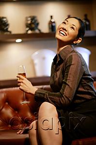 AsiaPix - Woman with champagne glass, legs crossed, looking up, smiling
