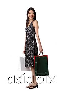 AsiaPix - Young woman standing with shopping bags, portrait