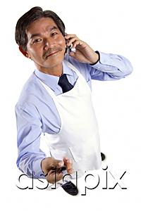 AsiaPix - Mature man wearing apron, using mobile phone, holding spatula looking at camera