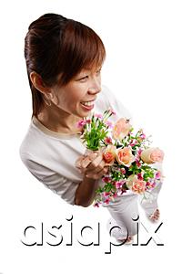 AsiaPix - Woman standing, holding bouquet of flowers, looking away