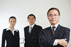 AsiaPix - Businessman with arms crossed, looking at camera, two executives behind him