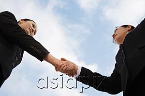 AsiaPix - Two businesswoman shaking hands, low angle view