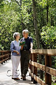 AsiaPix - Mature couple standing side by side, talking, woman holding book
