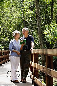 AsiaPix - Mature couple standing side by side, talking, woman looking at book