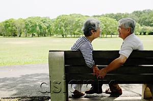 AsiaPix - Mature couple sitting face to face on park bench, holding hands