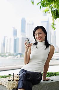 AsiaPix - Young woman, looking at mobile phone, buildings in the background