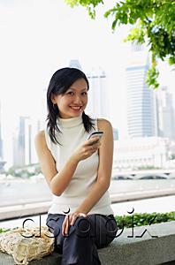AsiaPix - Young woman, holding mobile phone, looking at camera