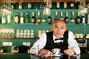 AsiaPix - Bartender behind bar counter, with cup and saucer