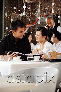 AsiaPix - Couple in restaurant, holding menu, smiling at each other