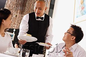 AsiaPix - Waiter serving plates of dessert  to customers in restaurant