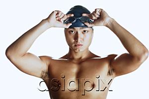 AsiaPix - Man adjusting swimming goggles, looking at camera, portrait