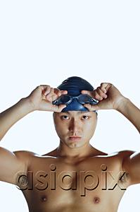 AsiaPix - Man touching swimming goggles, looking at camera, portrait