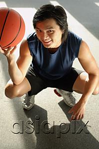 AsiaPix - Man crouching, holding basketball, looking up at camera