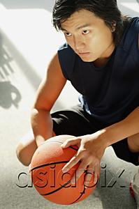 AsiaPix - Man crouching, holding basketball, portrait