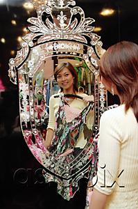 AsiaPix - Woman in clothing store, holding dress, looking at mirror