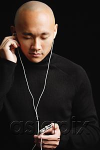 AsiaPix - Man with shaved head, listening to music with earphones