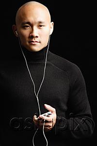 AsiaPix - Man with shaved head, listening to music with earphones, looking at camera