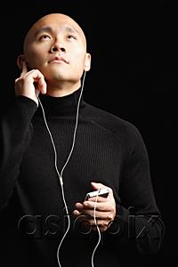 AsiaPix - Man with shaved head, listening to music with earphones, portrait