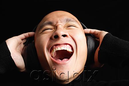 AsiaPix - Man with shaved head, wearing headphones, mouth open