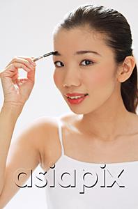 AsiaPix - Woman holding brush to eyebrows