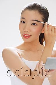 AsiaPix - Woman holding brush to eyebrows, compact mirror on other hand