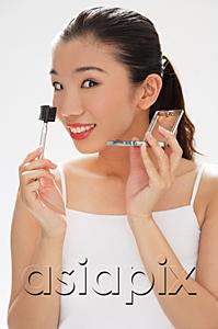 AsiaPix - Woman holding eyebrow brush and compact, smiling at camera