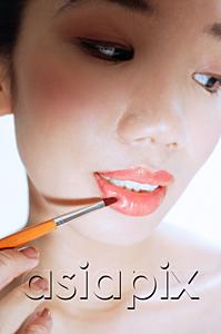 AsiaPix - Woman applying lipstick with lip brush