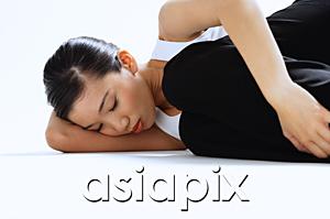 AsiaPix - Woman lying on side, hugging knee, eyes closed